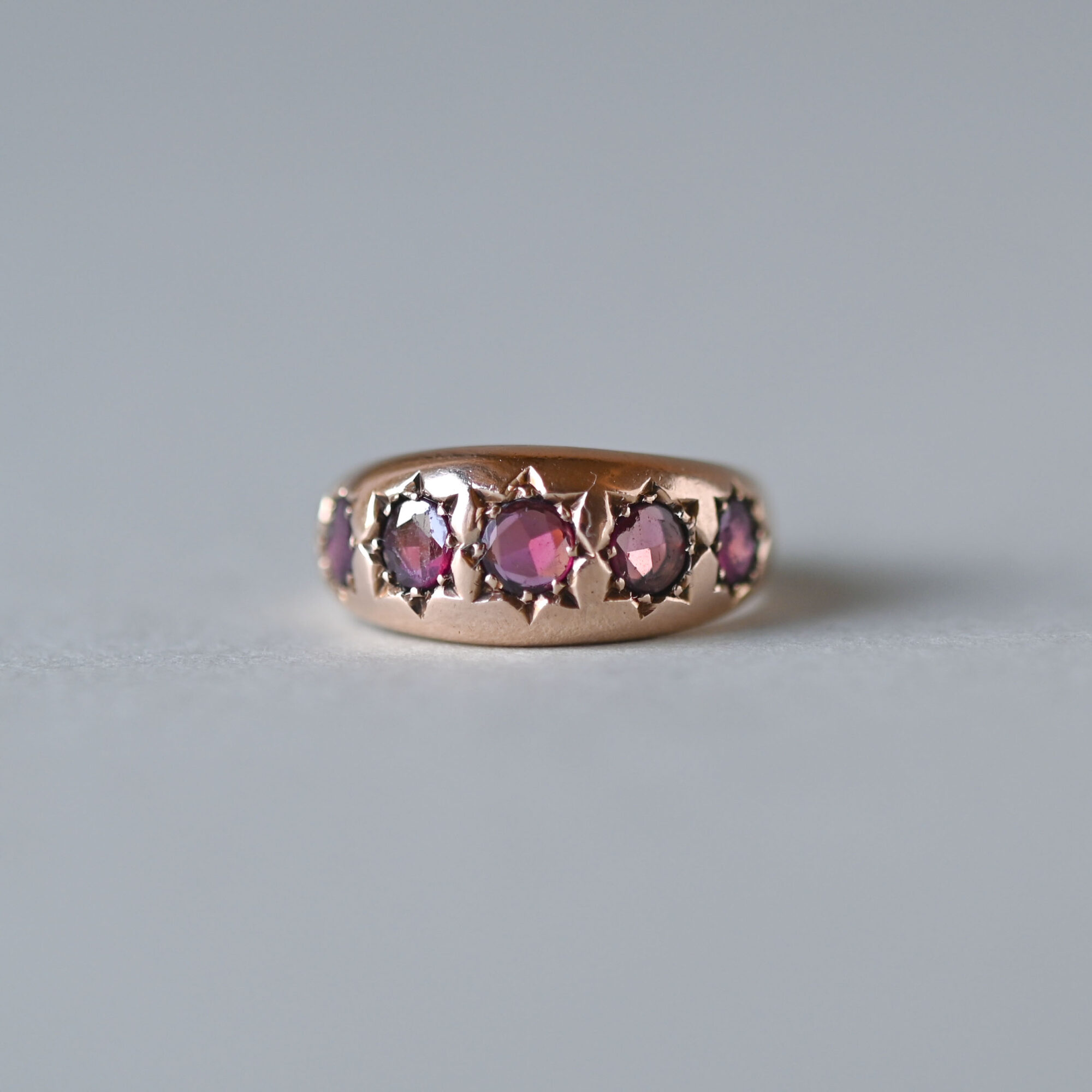 Celestial 9ct rose gold garnet starburst band ring, 1912