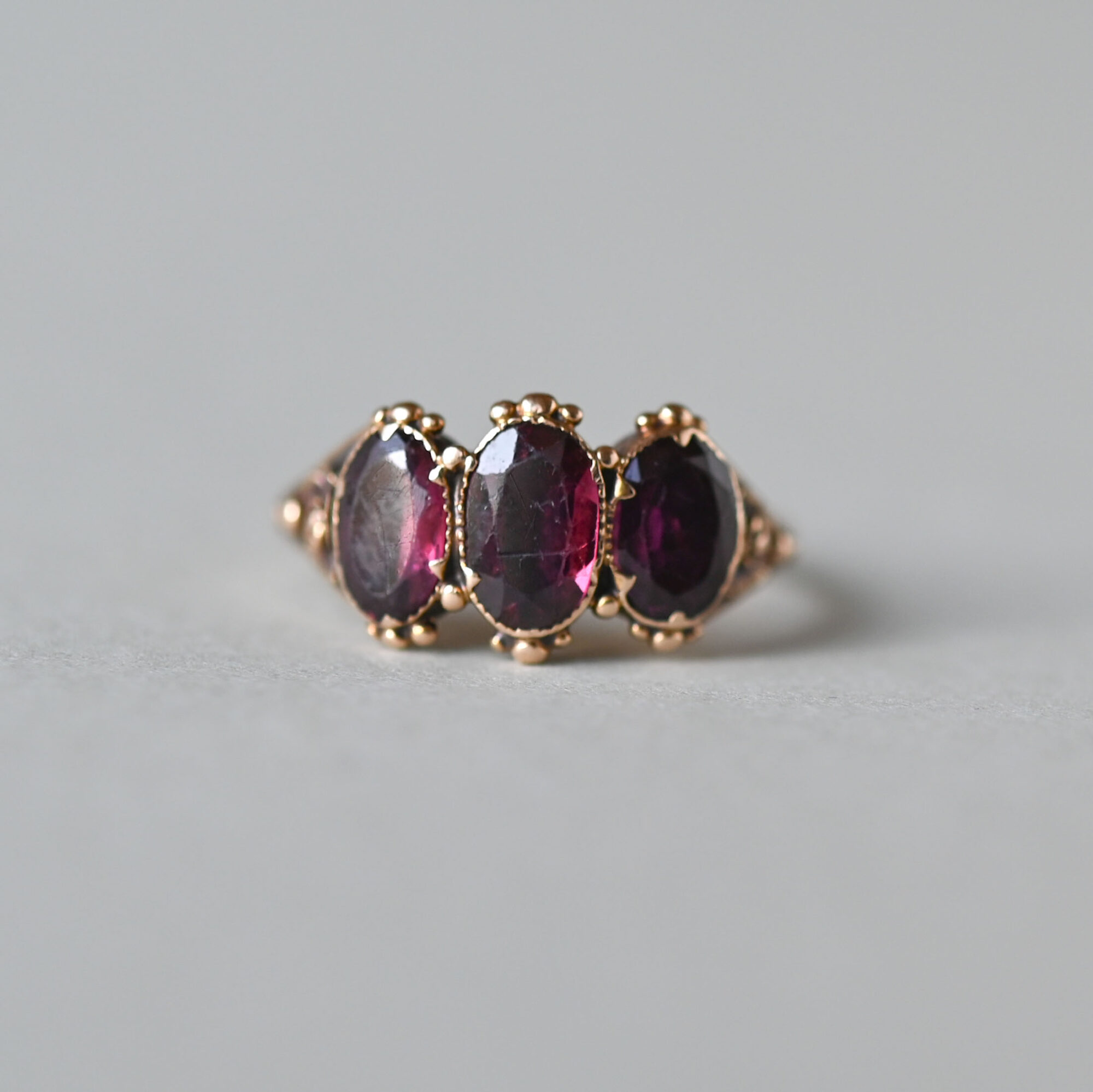 Early Victorian 18ct gold three stone garnet ring with granulation detailing, c.1840s