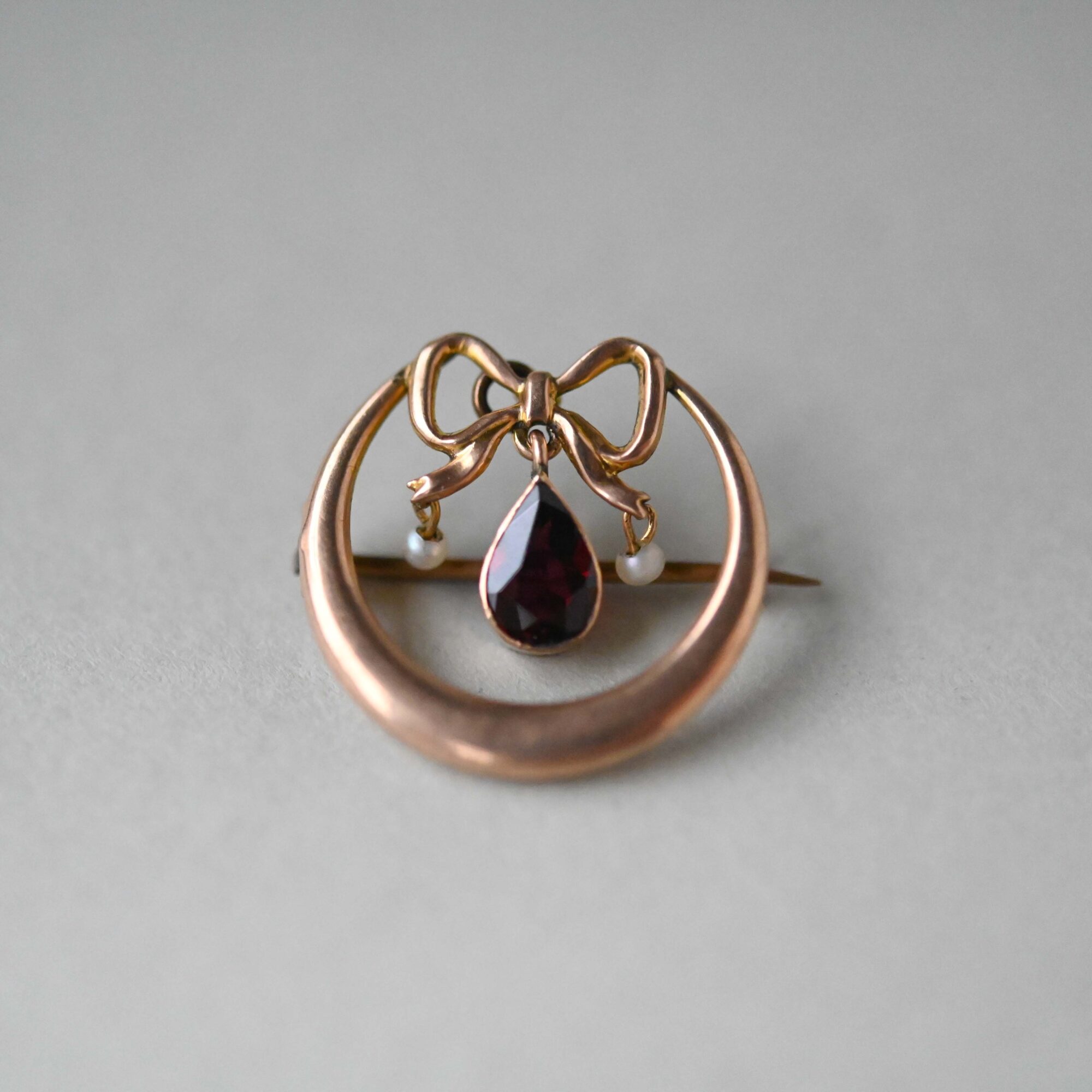 Edwardian 9ct gold honeymoon bow and crescent garnet brooch, c.1905